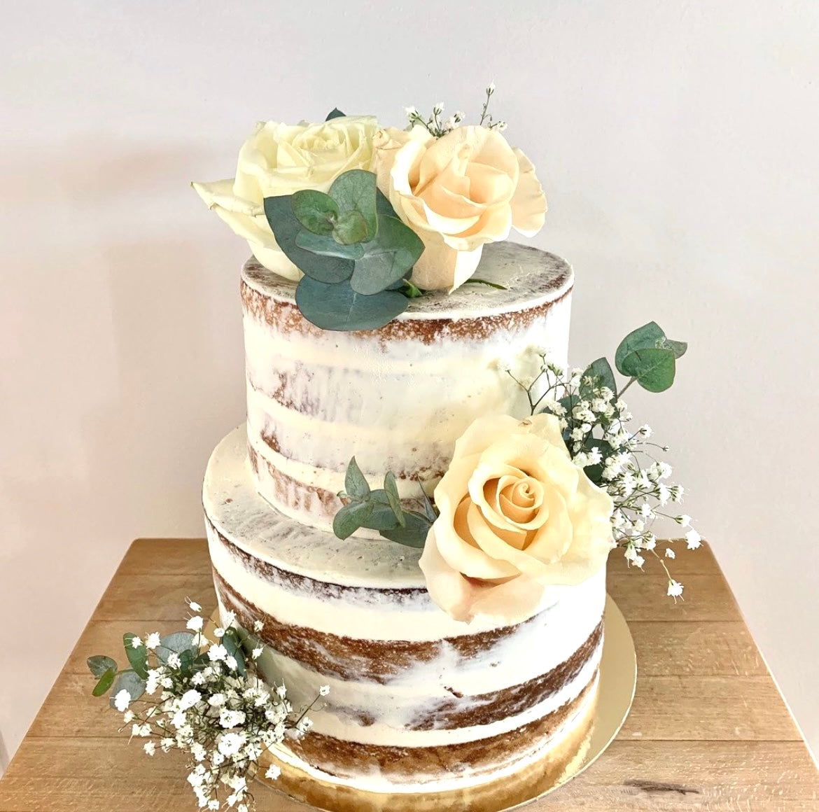 gateau de mariage wedding cake type naked cake avec des fleurs fraiches sur le dessus. Le gateau est composé d'une génoise nature, d'une crème chantilly et de fruits rouges. 