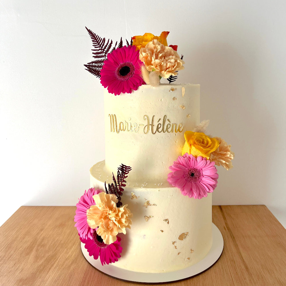 Naked cake theme fleuri sur deux étages avec des fleurs naturelles de couleurs roses et orange. 