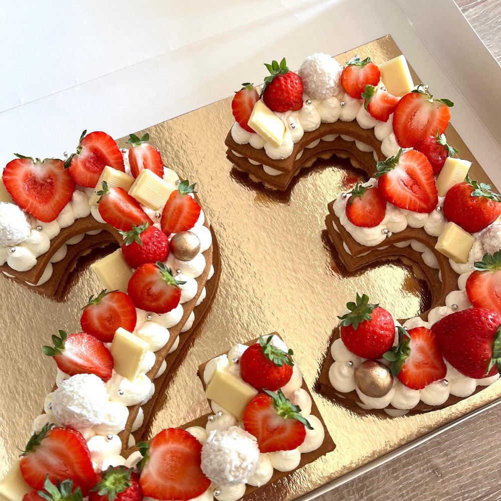 number cake nombre 23 avec une crème chantilly et des fraises fraîches sur le dessus. 