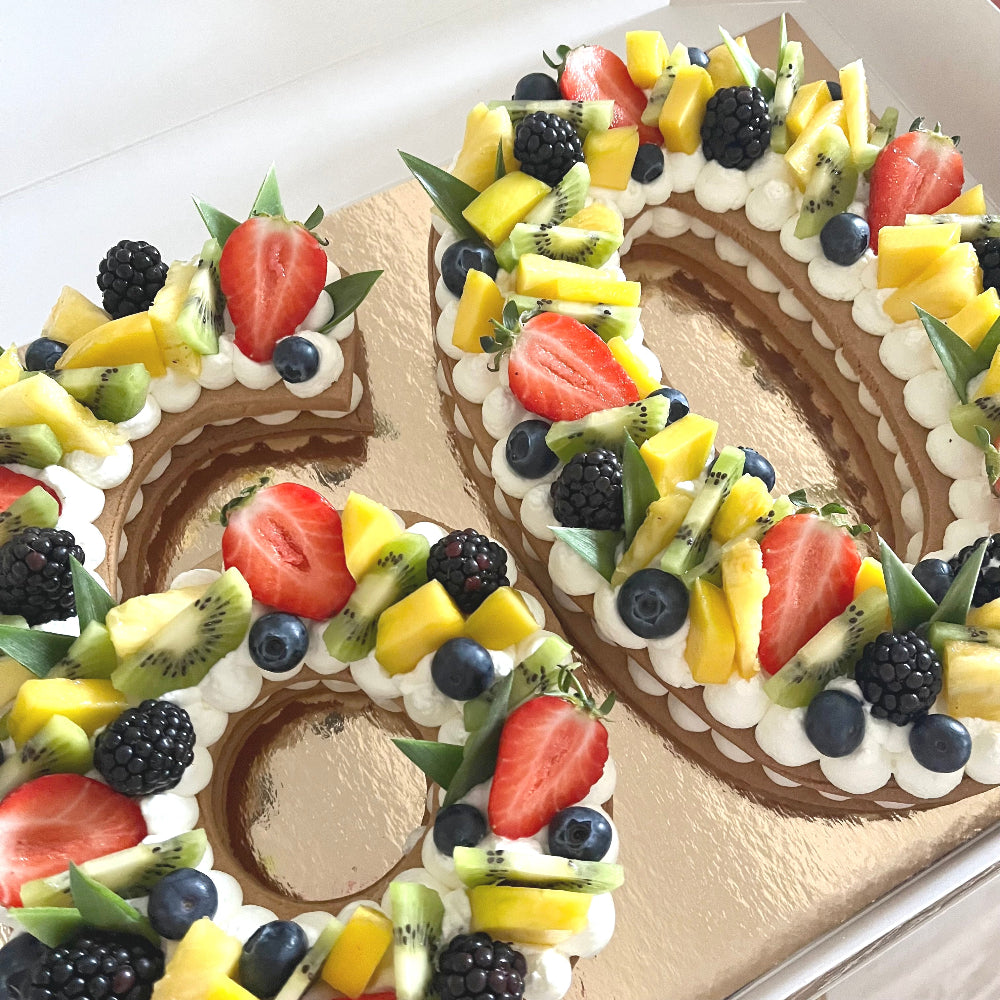 Number cake nombre 60 avec une chantilly et des fruits exotiques sur le dessus. 